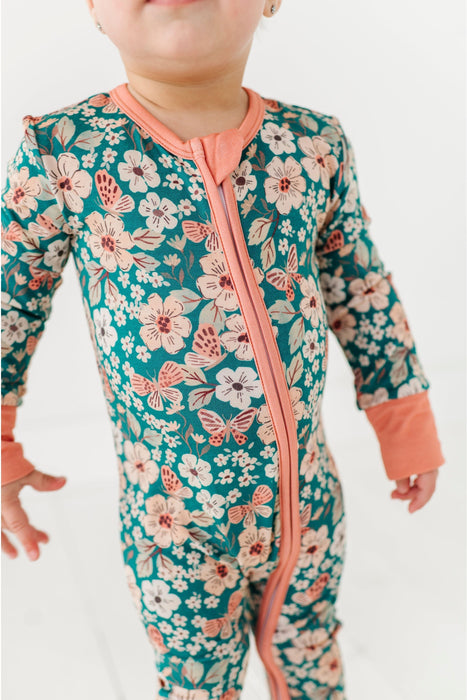 Child wearing a floral pj with a pink zipper on a white background by Bird and Bean