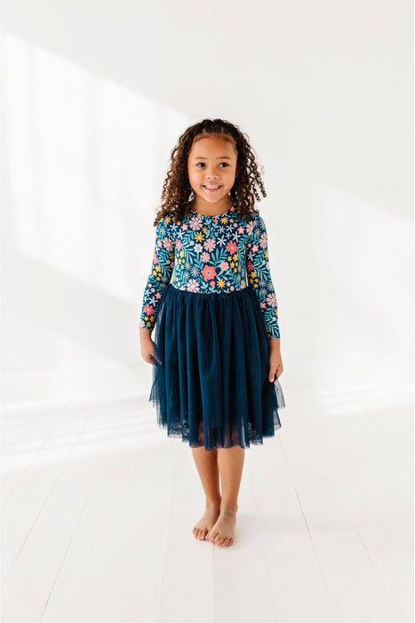 Young girl wearing a floral dress with dark blue tutu skirt on a white background by Bird and Bean