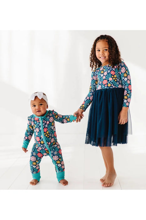 Child model in Maren Floral Navy Tulle Bamboo Dress with pink and gold flowers with baby model in matching one piece zip footie romper. .