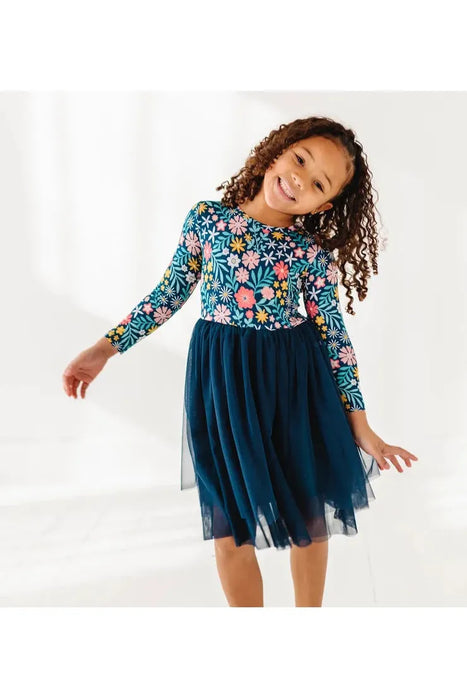 Child model in Maren Floral Navy Tulle Bamboo Dress with pink and gold flowers.