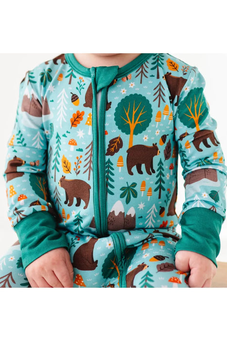 close up of Baby model wearing blue green bamboo pajama in Woody Woodland Bear print with mountains and mushrooms