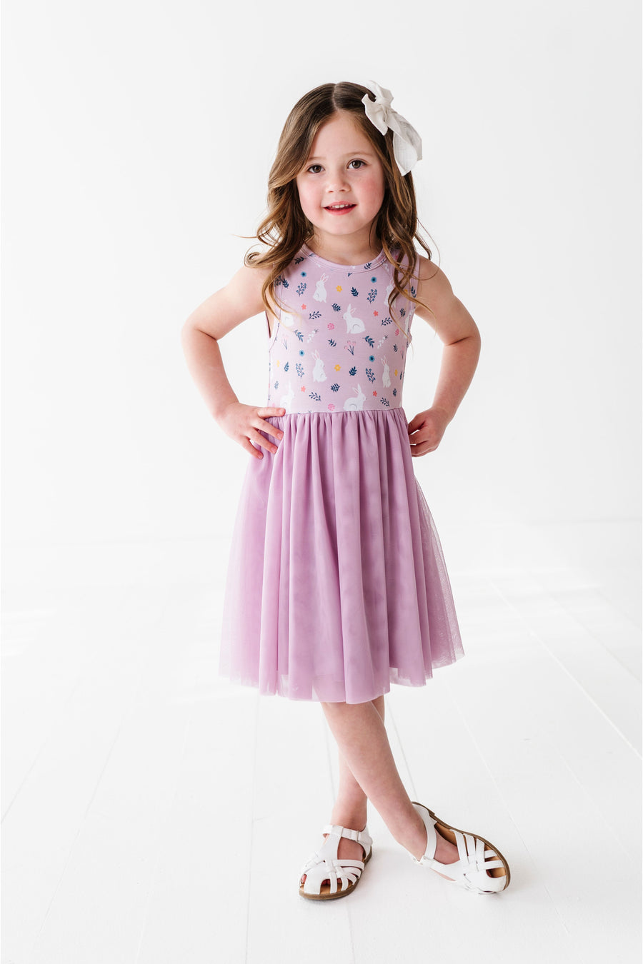 Young girl wearing a light purple tulle skirt dress with a floral headband on a white background - Bird and Bean Kids