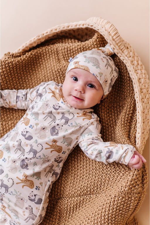 Newborn in a patterned bamboo sleeper outfit and hat sitting in a woven basket. Bird and Bean Kids