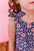 Child wearing a floral bamboo fabric dress  with bow tie shoulders with a pink background | Bird and Bean 