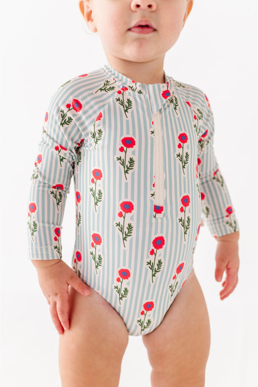 Child wearing a floral and striped zip front long sleeve swimsuit on a white background  Bird and Bean Kids