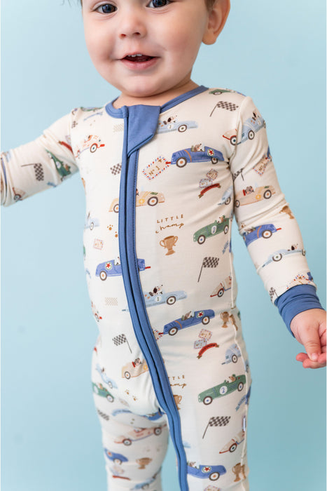 Baby wearing a bamboo pj zip front style with car pattern against a light blue background -Bird and Bean Baby 
