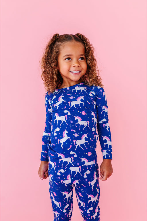 Child wearing a blue unicorn patterned  bamboo soft pajamas set on a pink background - Bird and Bean 