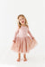 Young girl wearing a pink dress with a tulle skirt on a white background | Bird and Bean Holiday
