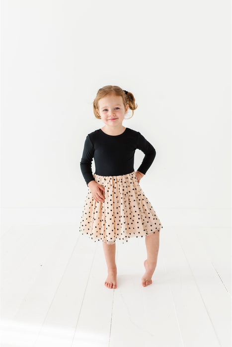 Young girl wearing a black long-sleeve top and polka dot skirt on a white background | Bird and Bean Holiday Shop