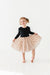 Young girl wearing a black long-sleeve top and polka dot  tulle skirt on a white background | Bird and Bean