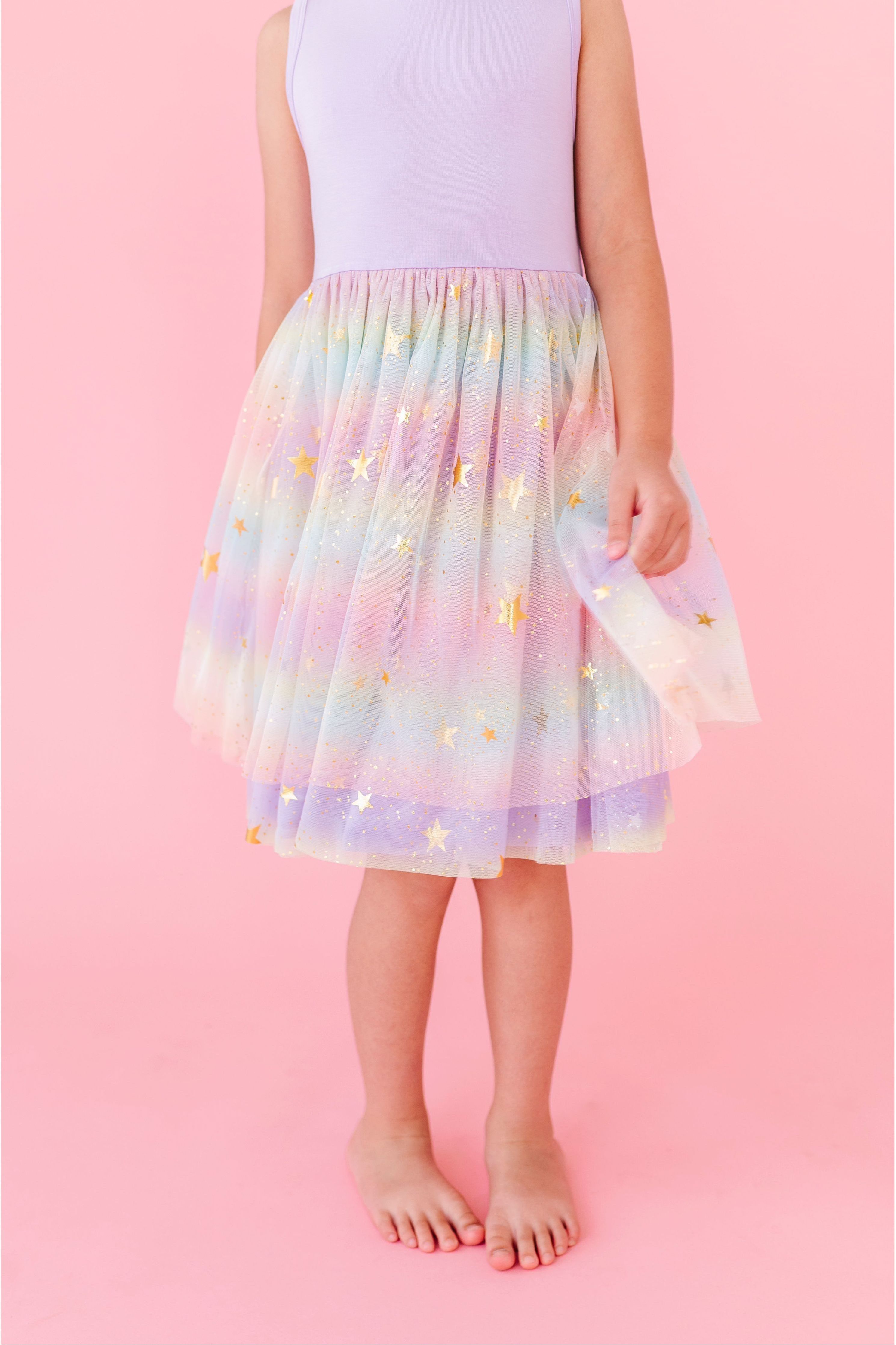 Pastel rainbow skirt  and bamboo top dress with star pattern worn by a child on a pink background. Bird and Bean exclusive print 