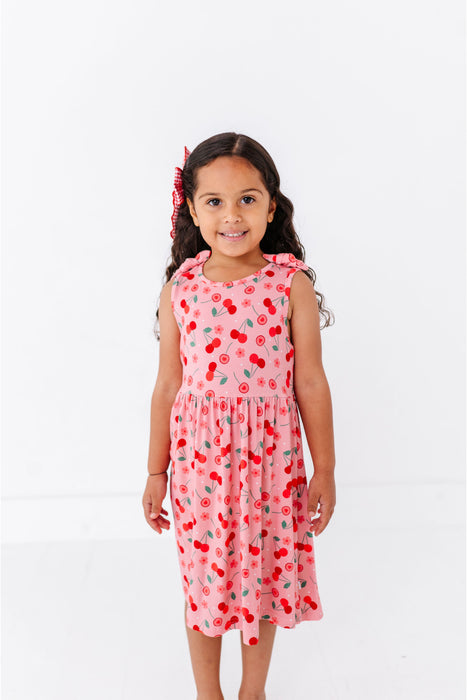 Young girl wearing a pink cherry print tank dress bamboo fabric  on a white background | Bird and Bean 