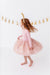 Young girl in a pink bamboo dress with gold sequins standing against a white background with gold decorations. | Bird and Bean Holiday Shop 
