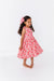 Young girl wearing a cherry print dress on a white background | Bird and Bean Kids