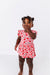 Child wearing a pink cherry print dress  on a white background | Bird and Bean Kids