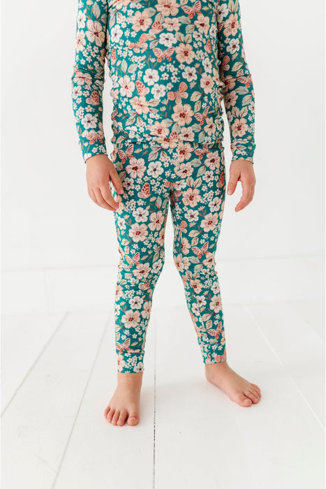 Child wearing a floral bird and bean brand pajama set on a white floor
