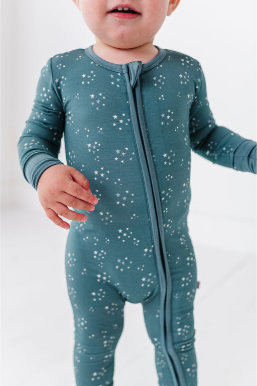 Child wearing a teal star bamboo onepiece with star pattern on a white background by Bird and Bean 