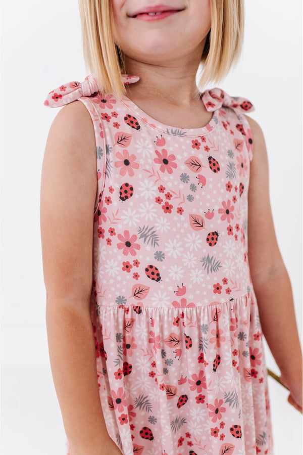 Child wearing a Harder floral print bamboo dress with pink flowers and ladybugs on a white background | Bird and Bean Original