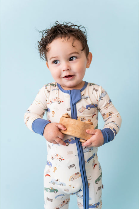 Child wearing a patterned zip pajamas holding a wooden toy against a light blue background Bird and Bean 