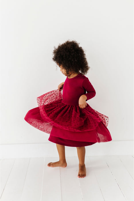 Child wearing a red dress with a lace overlay on a white background 
| Bird and Bean Holiday 