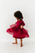 Child wearing a red dress with a lace overlay on a white background 
| Bird and Bean Holiday 