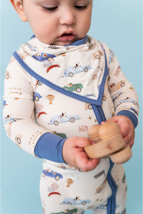 Baby wearing a patterned sleep suit and matching bib  with a blue trim, holding a wooden toy against a light blue background - Bird and Bean Baby 