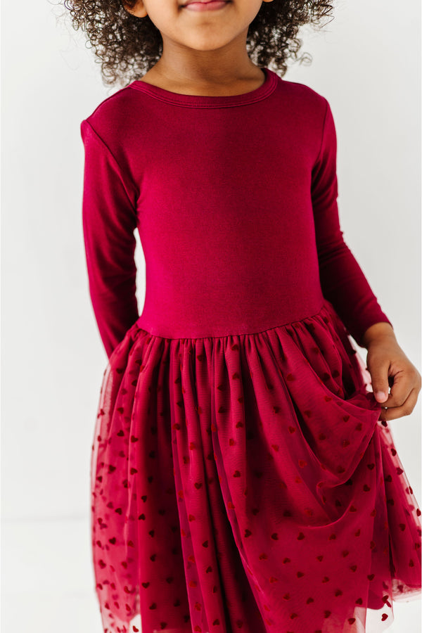 Child wearing a red dress with a tulle overlay on a white background | Bird and Bean 