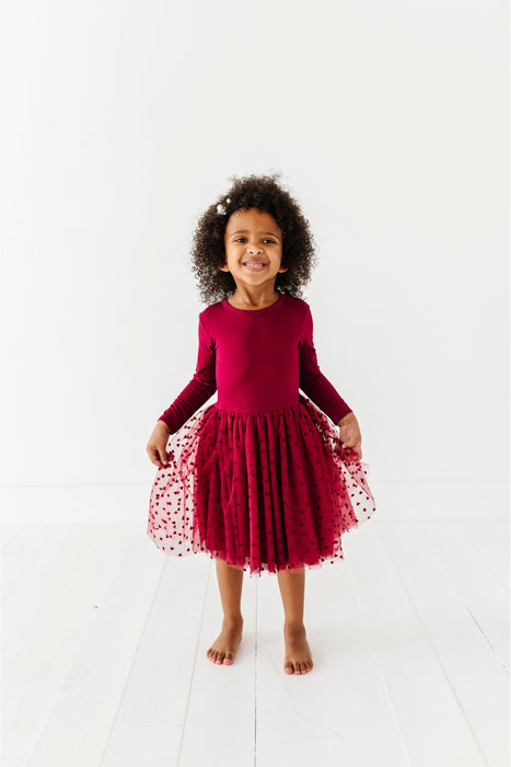 Young girl wearing a red dress with a tulle skirt on a white background | Bird and Bean Holiday 