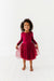 Young girl wearing a red dress with a tulle skirt on a white background | Bird and Bean Holiday 