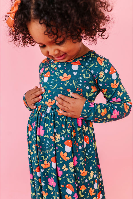 Child wearing a long-sleeve bamboo dress with a colorful mushroom pattern on a pink background | Bird and Bean 