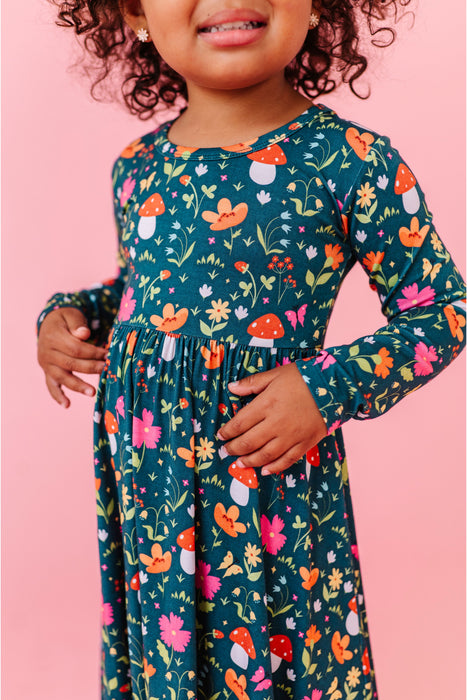 Child wearing a colorful floral bamboo dress  with long sleeves against a pink background | Bird and Bean 