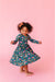 Child wearing a floral bamboo twirl dress on a pink background | Bird and Bean 