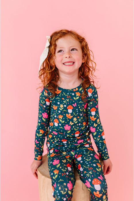 Child wearing a floral bamboo pajama set against a pink background | Bird and Bean 