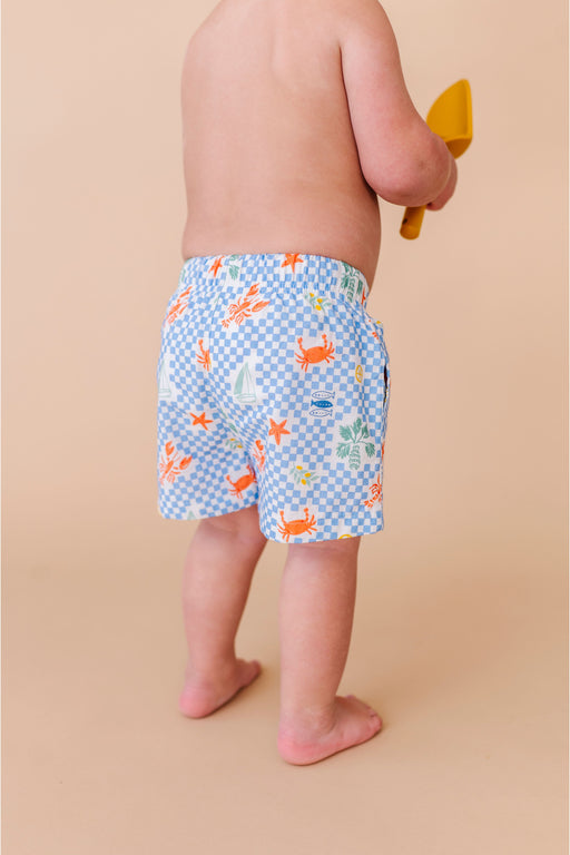 Child wearing blue swim shorts with animal pattern on a beige background Bird and Bean