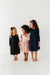 Three young girls wearing dresses standing on a white floor. | Bird and Bean Holiday