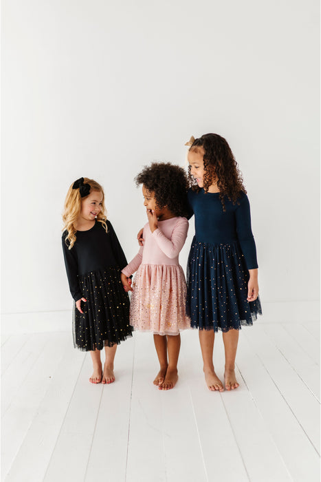 Three children wearing sparkly dresses standing on a white floor. | Bird and Bean Holiday