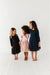 Three children wearing sparkly dresses standing on a white floor. | Bird and Bean Holiday