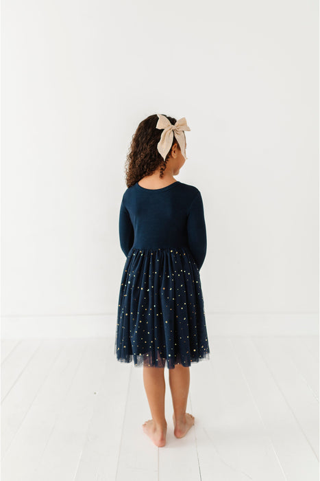 Child wearing a navy dress with star patterns on a white background | Bird and Bean 