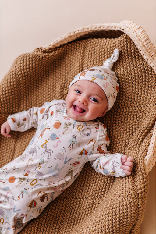 Baby in a patterned ABC bamboo newborn outfit and hat lying on a blanket - Bird and Bean