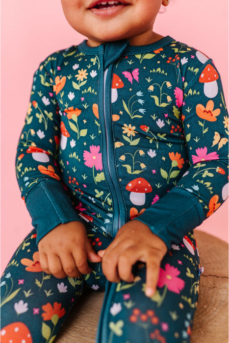 Child wearing a colorful floral and mushroom patterned outfit on a pink background | Bird and Bean 