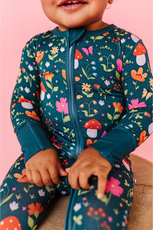 Child wearing a colorful floral and mushroom patterned outfit on a pink background | Bird and Bean 