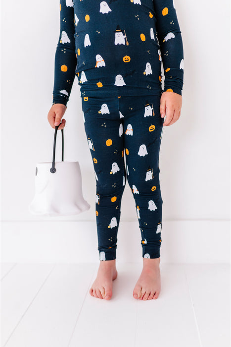 Child wearing Halloween-themed pajamas with ghosts, pumpkins, and cats on a white background