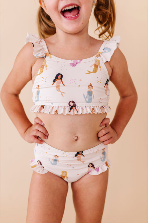 Child wearing a mermaid-themed two-piece swimsuit on a beige background Bird and Bean