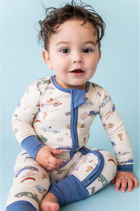 Baby wearing a patterned zip pj with blue accents on a light blue background - Bird and Bean Baby 