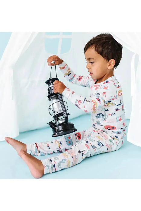 Child model sitting in prop tent wearing Bamboo Desert Adventure Happy Camper Tents and Cactus Kids Pajama Set holding lantern