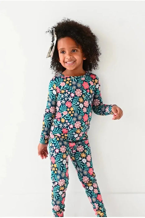 Child model standing in Bamboo Maren Peach, gold, and pink flower navy blue pajama set