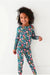 Child model standing in Bamboo Maren Peach, gold, and pink flower navy blue pajama set