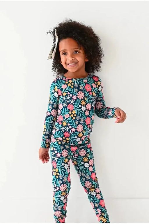 Child model standing in Bamboo Maren Peach, gold, and pink flower navy blue pajama set