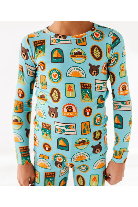 Close up of Kid model wearing bamboo pajamas featuring bright, adorable illustrated adventure merit patches in Let's Explore print