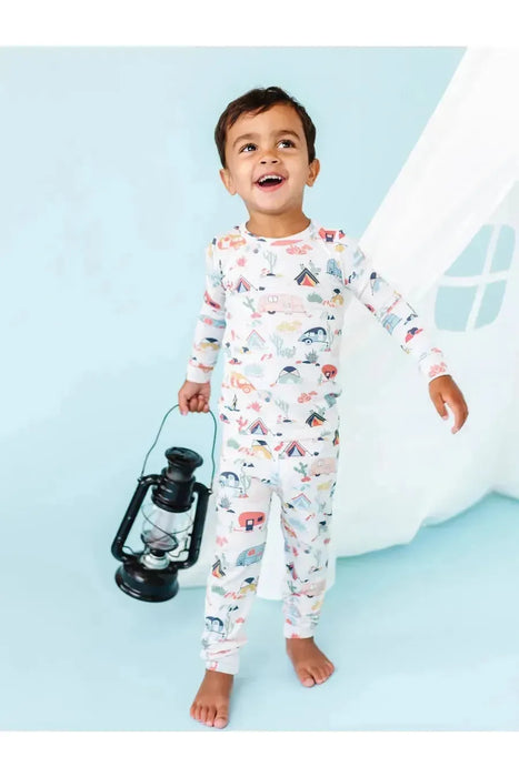Kid model wearing Bamboo Desert Adventure Happy Camper Tents and Cactus Kids Pajama Set holding lantern in front of studio set